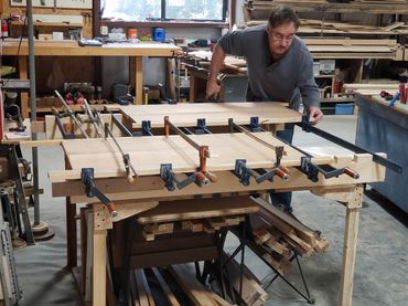 Dennis at the glue table gluing solid edges onto the bookshelf panels.