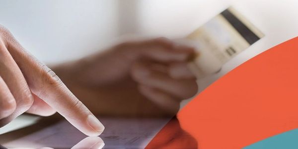 Person using a touchscreen device while holding a credit card.