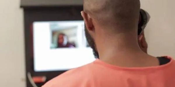 Man with shaved head and beard looking at a screen.