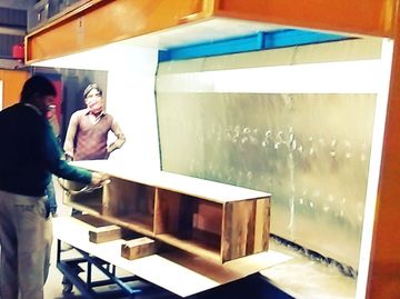 Two men inspecting a wooden cabinet in a workshop.
