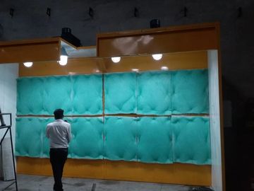 Man standing in front of a large green and orange padded wall.