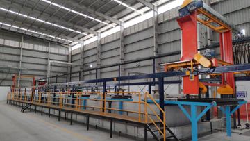 A large industrial surface treatment plant with metal tanks and machinery inside a warehouse.