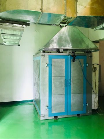 Industrial metal machine with blue doors and ventilation ducts in a clean room.