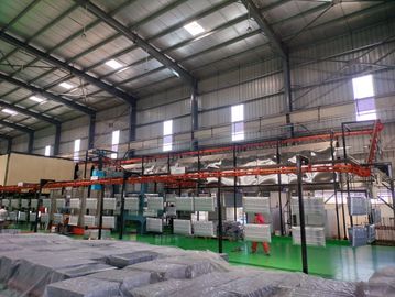 Industrial facility with hanging metal panels on a conveyor system inside a spacious warehouse.