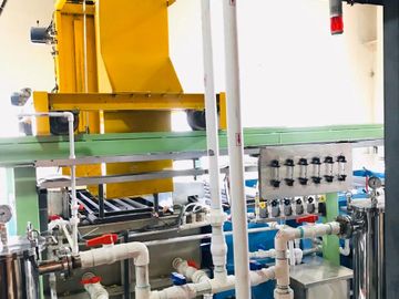 Industrial machinery with interconnected pipes and valves in a factory setting.