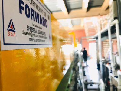 Close-up of a yellow industrial machine with a "FORWARD" label in a factory setting.