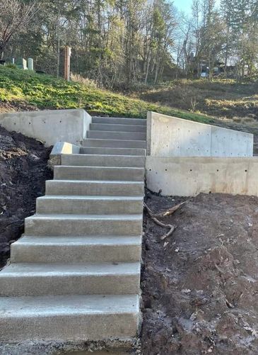 Concrete stairs with a landing and retaining walls on a hillside.