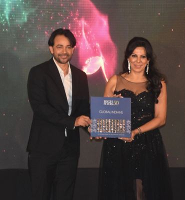 A man and woman holding a 'High Flyers 50 Global Indians' award plaque together.