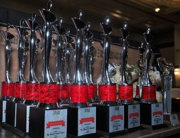 A row of shiny silver trophies with red accents displayed on a table.