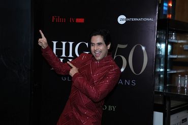 Man in a sparkling red outfit poses joyfully at an event.
