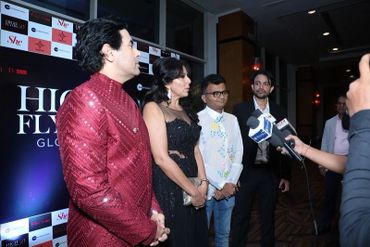 Four people dressed formally, one giving an interview with microphones.