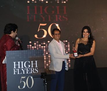 Award ceremony at High Flyers 50 event with a woman receiving a trophy.