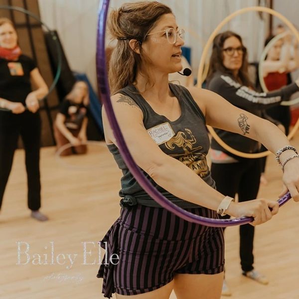 Woman leading a hula hoop class indoors.
