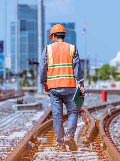 Trabajador de la construccion caminando sobre via ferroviaria