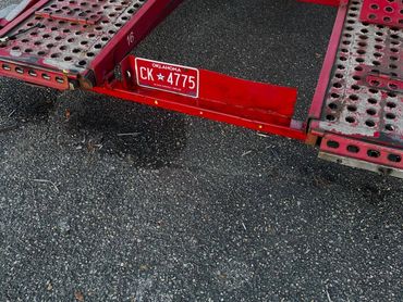 Red trailer with Oklahoma license plate CK 4775 on asphalt.