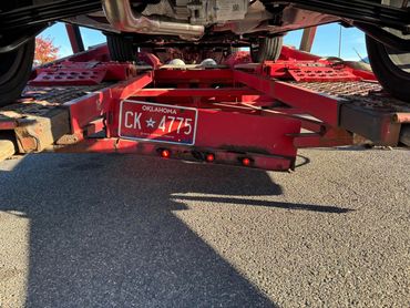 View under a vehicle on a red trailer with Oklahoma license plate CK 4775.