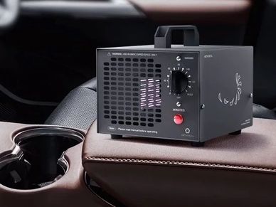 A compact black ozone generator placed on a car armrest.