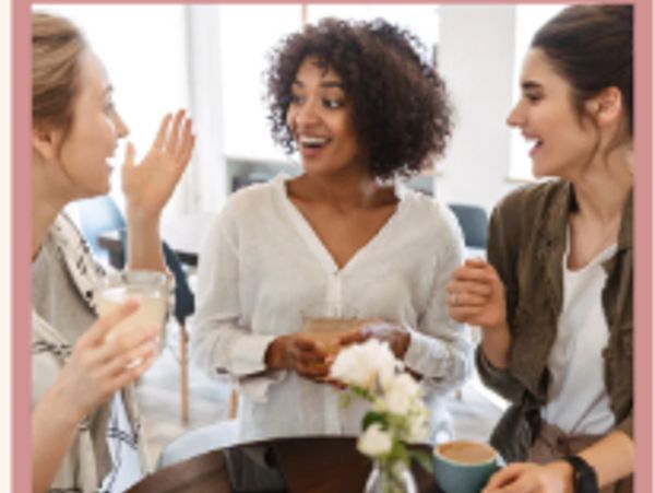 Three women happily chatting over coffee in a cozy setting.