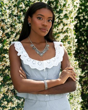 Woman in scalloped collar dress wearing silver statement necklace and bracelet.