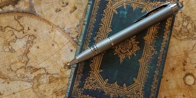 A leather notebook with a pen on an ancient map.