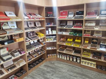 Corner of the shop showing wood shelving stocked with tobacco products
