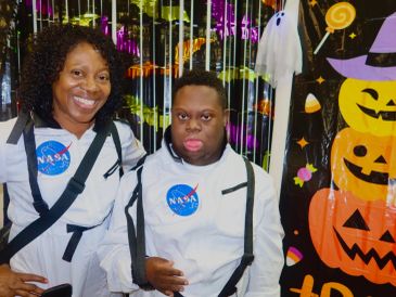 Two people dressed in NASA astronaut costumes at a Halloween event.