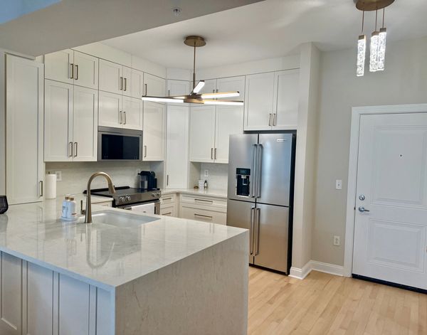 Modern kitchen with white cabinets and marble island.