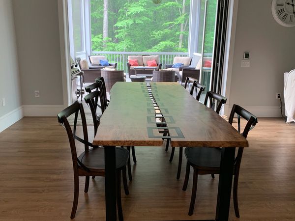 Wooden dining table with black chairs in a spacious room leading to a porch with seating.