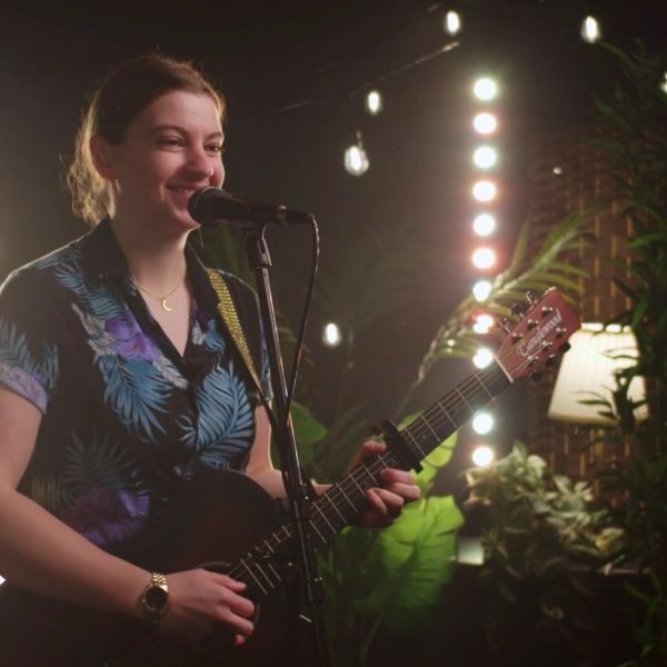 Young woman singing and playing guitar on stage.