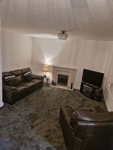 Cozy living room with brown leather sofas and a modern fireplace.
