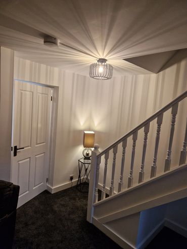 Cozy stairway corner illuminated by artistic ceiling and table lamps.