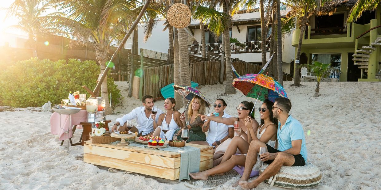 Amigos comiendo en la playa junto a palmeras