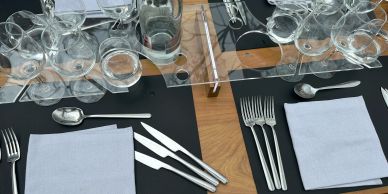 Wine glasses and water bottle on a wooden table set for dining on a Bustronome bus.