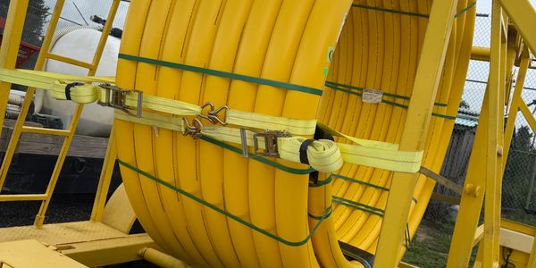 Coiled yellow industrial hose secured with straps.