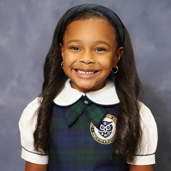 Smiling schoolgirl in uniform with long hair and headband.