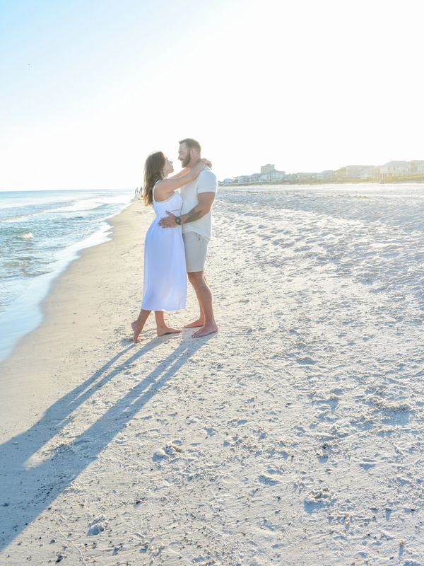 Couple embracing on a sunny beach with long shadows.