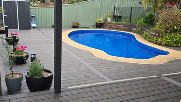 Modern backyard with a kidney-shaped pool and wooden deck surrounded by plants.