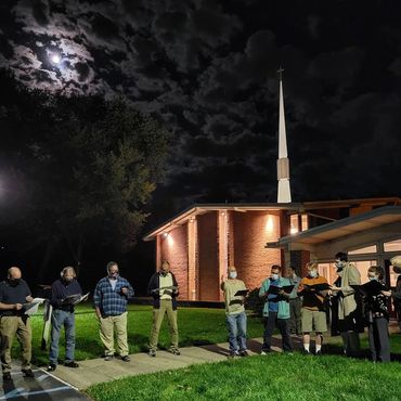 The men wearing masks and rehearsing outside in front of a church under a full moon