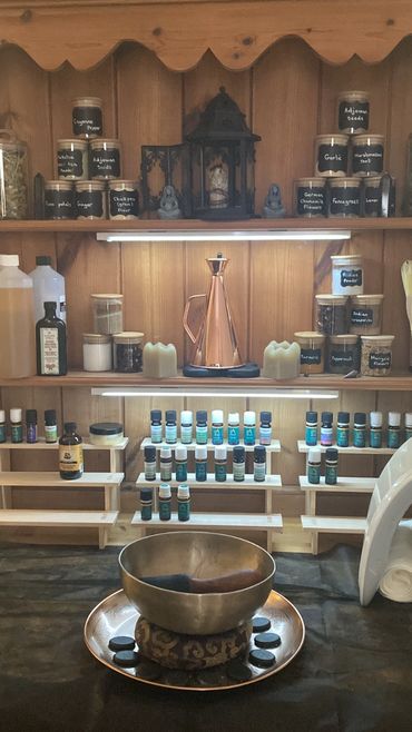 A serene setup with essential oils, herbs, and a singing bowl for relaxation and healing.