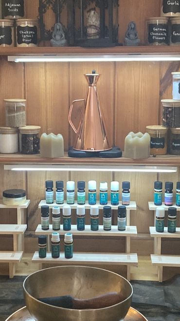 A serene setup with essential oils, herbs, and a singing bowl for relaxation and healing.