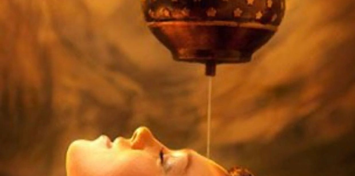 Person receiving traditional Ayurvedic oil therapy.