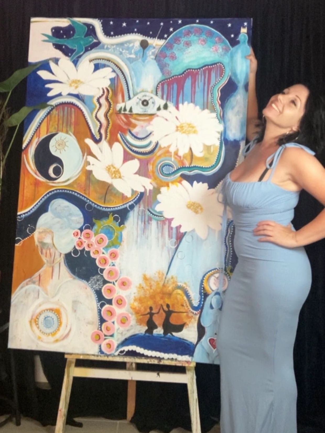 Woman in blue dress posing with colorful abstract painting.