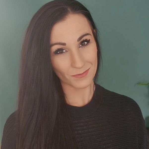 Woman with long dark hair and a subtle smile against a teal background.