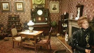 Victorian-style room with antique furniture and a mannequin in period clothing.
