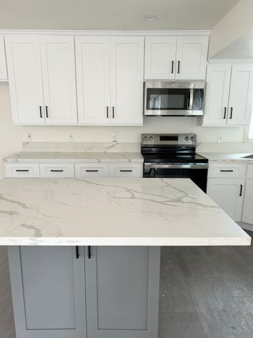 Modern kitchen with white cabinets and marble countertops.