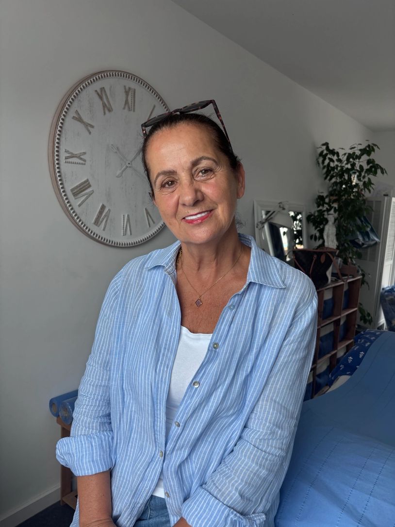 Smiling woman in a blue striped shirt indoors.
