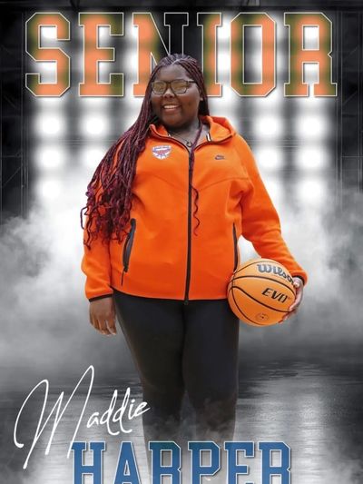 Senior basketball player Maddie Harper posing with a basketball in an orange jacket.