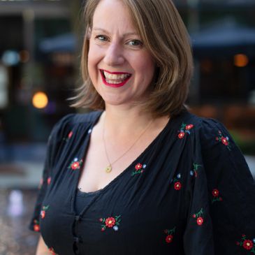 Smiling woman in a black floral dress.