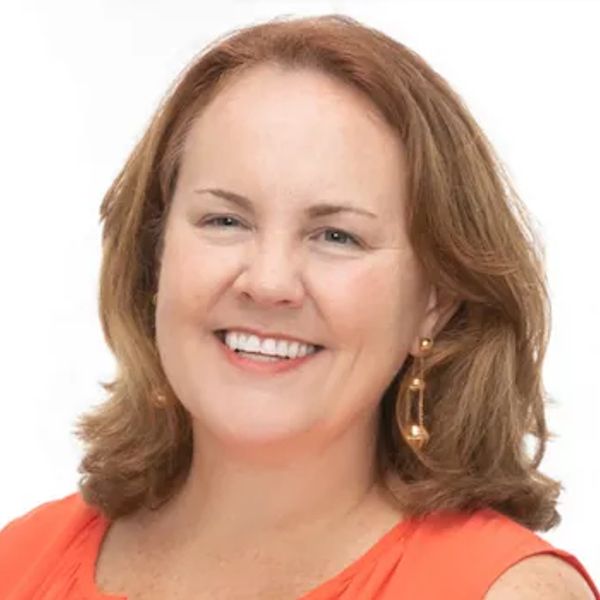 Smiling woman with light brown hair and orange top.