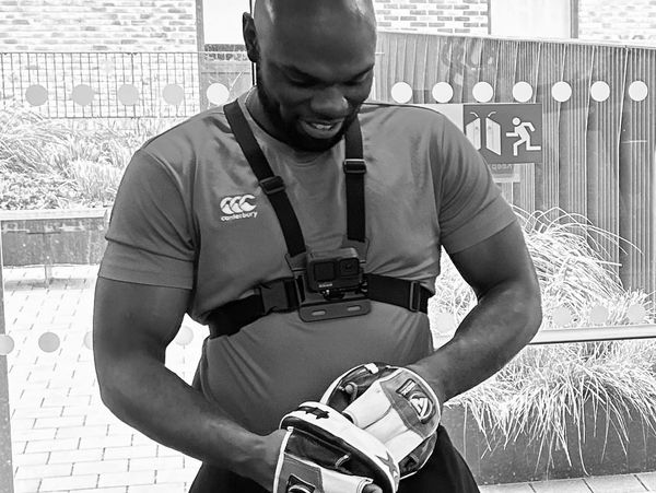 man smiling while putting on boxing pads